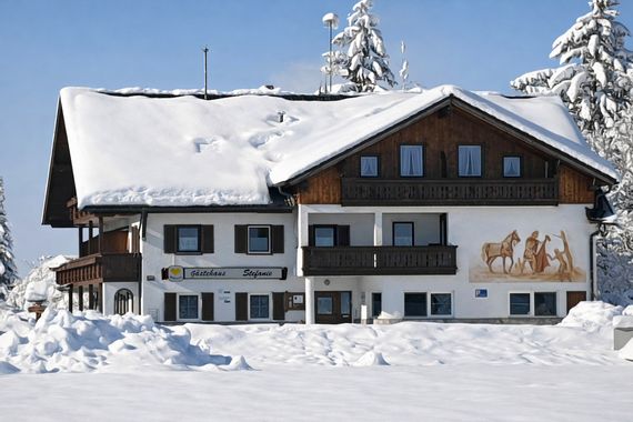 Das Gästehaus Stefanie in Schwangau-Brunnen mit schneebedecktem Dach im Winter.