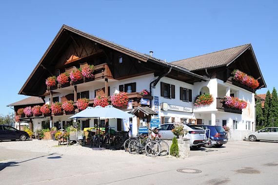 Das Gästehaus Stefanie in Brunnen mit Blumenbalkonen unter blauem Himmel.
